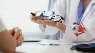 Kadın doktor danışmanlık için göz modelini tutuyor. Yaşlı bir kadın görüşü hakkında doktora danışıyor. Yaşlılar için tıbbi teşhis. Anatomi. Göz modeli.