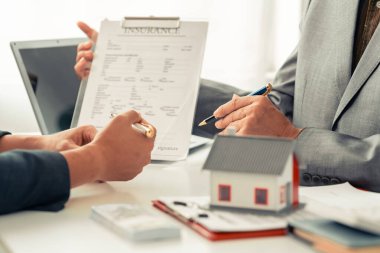 Emlak işadamı ev kredisi sunuyor ve onaylanmış başvuru formunu tartıştıktan ve imzaladıktan sonra ev müşteriye sunuyor. Kapat..