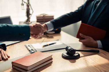 Avukat ekibi, ofisteki müşteriye imzalı sözleşme belgesini sunuyor. Hukuk, yargıç, mahkeme, hukuk kavramı. Yargıcın adalet terazisiyle tokmağı. Kapat..