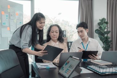 Asyalı iş adamları başarılı takım çalışmalarının sonuçlarını, yatırımları ve takım çalışmasının sonuçlarını gösteren grafikleri ve grafikleri tartışıyor..