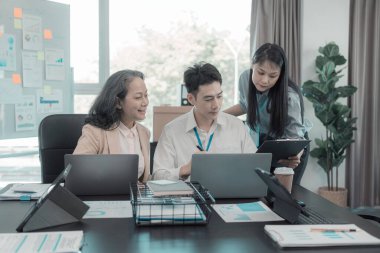 Asyalı iş adamları başarılı takım çalışmalarının sonuçlarını, yatırımları ve takım çalışmasının sonuçlarını gösteren grafikleri ve grafikleri tartışıyor..