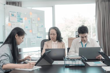 Asyalı iş adamları başarılı takım çalışmalarının sonuçlarını, yatırımları ve takım çalışmasının sonuçlarını gösteren grafikleri ve grafikleri tartışıyor..