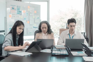 Asyalı iş adamları başarılı takım çalışmalarının sonuçlarını, yatırımları ve takım çalışmasının sonuçlarını gösteren grafikleri ve grafikleri tartışıyor..