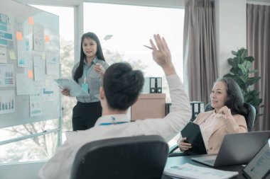 Asyalı iş adamları başarılı takım çalışmalarının sonuçlarını, yatırımları ve takım çalışmasının sonuçlarını gösteren grafikleri ve grafikleri tartışıyor..