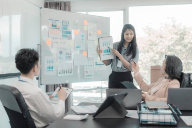 Asyalı iş adamları başarılı takım çalışmalarının sonuçlarını, yatırımları ve takım çalışmasının sonuçlarını gösteren grafikleri ve grafikleri tartışıyor..