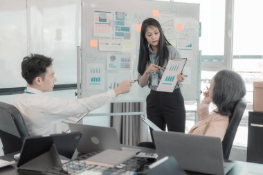 Asyalı iş adamları başarılı takım çalışmalarının sonuçlarını, yatırımları ve takım çalışmasının sonuçlarını gösteren grafikleri ve grafikleri tartışıyor..