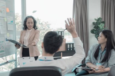 Asyalı iş adamları başarılı takım çalışmalarının sonuçlarını, yatırımları ve takım çalışmasının sonuçlarını gösteren grafikleri ve grafikleri tartışıyor..