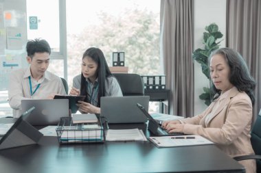 Asyalı iş adamları başarılı takım çalışmalarının sonuçlarını, yatırımları ve takım çalışmasının sonuçlarını gösteren grafikleri ve grafikleri tartışıyor..