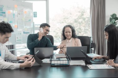 Asyalı iş adamları başarılı takım çalışmalarının sonuçlarını, yatırımları ve takım çalışmasının sonuçlarını gösteren grafikleri ve grafikleri tartışıyor..