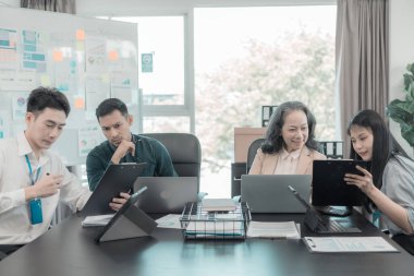 Asyalı iş adamları başarılı takım çalışmalarının sonuçlarını, yatırımları ve takım çalışmasının sonuçlarını gösteren grafikleri ve grafikleri tartışıyor..