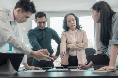 Asyalı iş adamları başarılı takım çalışmalarının sonuçlarını, yatırımları ve takım çalışmasının sonuçlarını gösteren grafikleri ve grafikleri tartışıyor..