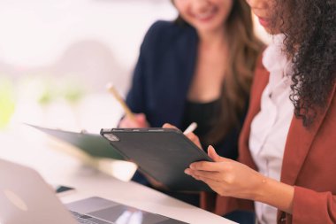 Takım elbiseli iki iş kadını bilgisayar teknolojisi belgelerini kullanarak modern ofisteki analiz için beyin fırtınası yapıyorlar.