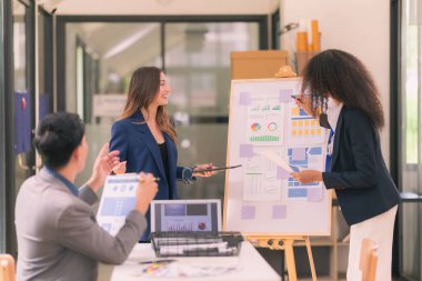 Bir grup iş adamı, ofiste tabletle çalışan grafik tasarımlı başarılı takım çalışmasının sonucunu temsil eden bir ürün tasarlıyor..