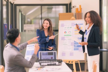 Bir grup iş adamı, ofiste tabletle çalışan grafik tasarımlı başarılı takım çalışmasının sonucunu temsil eden bir ürün tasarlıyor..