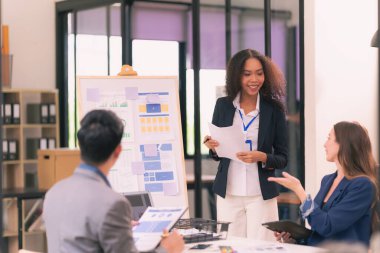 Bir grup iş adamı, ofiste tabletle çalışan grafik tasarımlı başarılı takım çalışmasının sonucunu temsil eden bir ürün tasarlıyor..