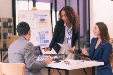 Bir grup iş adamı, ofiste tabletle çalışan grafik tasarımlı başarılı takım çalışmasının sonucunu temsil eden bir ürün tasarlıyor..