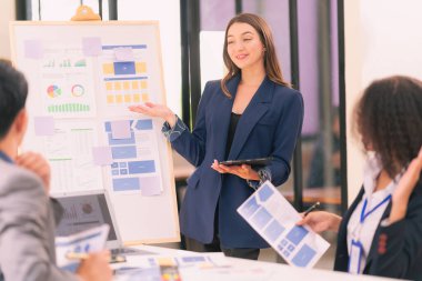 Bir grup iş adamı, ofiste tabletle çalışan grafik tasarımlı başarılı takım çalışmasının sonucunu temsil eden bir ürün tasarlıyor..