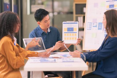 Bir grup iş adamı, ofiste tabletle çalışan grafik tasarımlı başarılı takım çalışmasının sonucunu temsil eden bir ürün tasarlıyor..