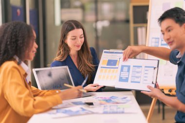 Bir grup iş adamı, ofiste tabletle çalışan grafik tasarımlı başarılı takım çalışmasının sonucunu temsil eden bir ürün tasarlıyor..