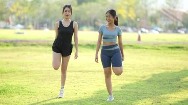 İki Asyalı kadın spor yapıyor, koşuyor, esniyor ya da akşamları parkta birlikte spor yapıyor..