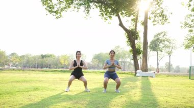 İki Asyalı kadın spor yapıyor, koşuyor, esniyor ya da akşamları parkta birlikte spor yapıyor..