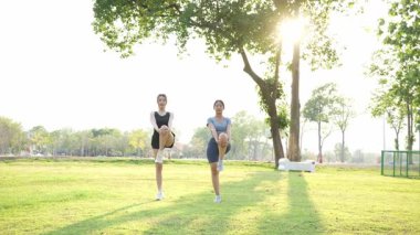 İki Asyalı kadın spor yapıyor, koşuyor, esniyor ya da akşamları parkta birlikte spor yapıyor..