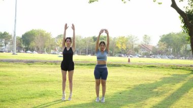 İki Asyalı kadın spor yapıyor, koşuyor, esniyor ya da akşamları parkta birlikte spor yapıyor..
