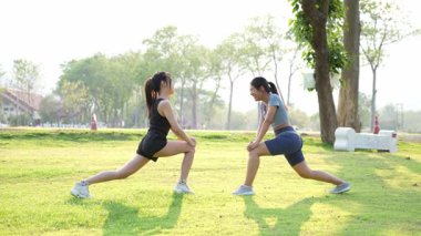 İki Asyalı kadın spor yapıyor, koşuyor, esniyor ya da akşamları parkta birlikte spor yapıyor..