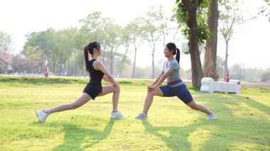 İki Asyalı kadın spor yapıyor, koşuyor, esniyor ya da akşamları parkta birlikte spor yapıyor..