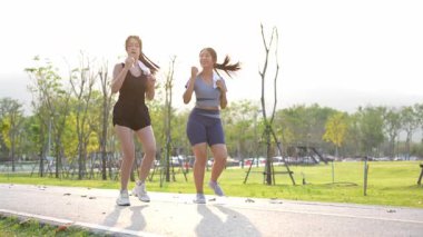 İki Asyalı kadın spor yapıyor, koşuyor, esniyor ya da akşamları parkta birlikte spor yapıyor..