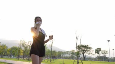 Güzel Asyalı bayan koşucu yazın parkta koşuyor, pozitif bir tavırla sağlıklı bir hayat sürüyor. Egzersiz rahatlatıcı ve mutludur..