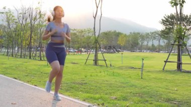 Güzel Asyalı bayan koşucu yazın parkta koşuyor, pozitif bir tavırla sağlıklı bir hayat sürüyor. Egzersiz rahatlatıcı ve mutludur..
