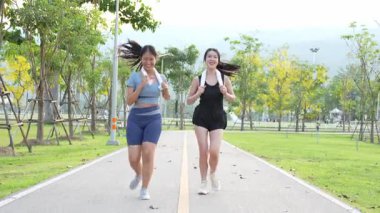 İki Asyalı kadın spor yapıyor, koşuyor, esniyor ya da akşamları parkta birlikte spor yapıyor..