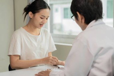 Doktor ve hasta masada otururken bir şey tartışıyorlar. Tıp ve sağlık hizmetleri kavramı. Erkek doktor, kadın hastaya teşhisi açıklıyor. Tıp ve sağlık hizmetleri kavramı.