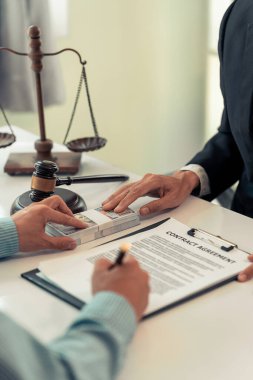 Danışmanlık ve Adalet. Avukat ve iş adamı danışmanlık ve müzakere yapıyor. Tokmağın yakın çekimi. Erkek avukat ya da yargıç, modern ofisteki evrak masasında dava okuyor..