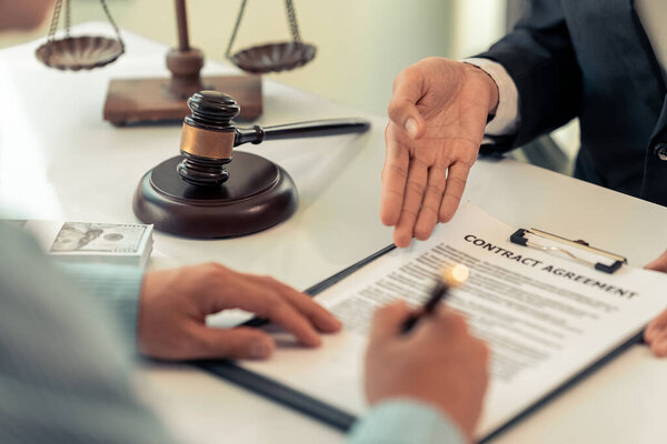 Консультации и правосудие. Юрист и бизнесмен, работающий консультантом и ведущим переговоры. Крупный план молотка. Мужской адвокат или судья, читающий дело в документах на столе в современном офисе.