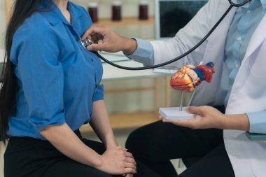 Doktorun steteskop tutarak özel klinikteki orta yaşlı erkek hastanın nabzını kontrol etmesine yakın çekim. Hemşire kişisel tıbbi bakım sağlıyor. Doktor kalp hastalığı konseptini kontrol ediyor..