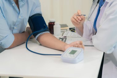 Hastanedeki hastanın kolundaki kan basıncını ölçmek için tansiyon monitörü ve steteskop kullanan doktor. Kapat..