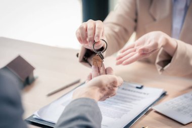 Emlakçının yeni evin anahtarlarını vermesi, ipotek kredisini ve faiz oranını analiz etmesi, yatırım planlaması, gayrimenkul, ev satın alma ve satış konseptini kapatması.