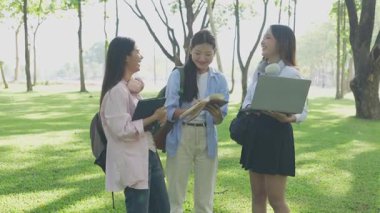 Laptopları ve tablet bilgisayarları olan bir grup üniversite öğrencisi parkta ödev yapıyor, dışarıda bir ağacın altında konuşuyor ve birlikte çalışıyorlar..