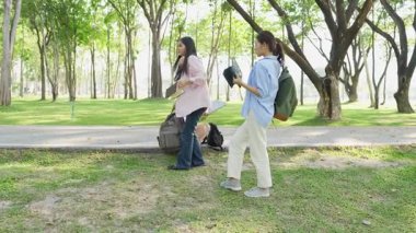 Laptopları ve tablet bilgisayarları olan bir grup üniversite öğrencisi parkta ödev yapıyor, dışarıda bir ağacın altında konuşuyor ve birlikte çalışıyorlar..