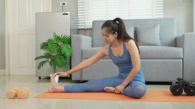 Sağlık, fitness konsepti. Aktif Asyalı bayan sporcu evde egzersiz yapıyor, mindere oturuyor. Spor ve spor rutini.