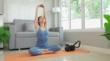 Sağlık, fitness konsepti. Aktif Asyalı bayan sporcu evde egzersiz yapıyor, mindere oturuyor. Spor ve spor rutini.