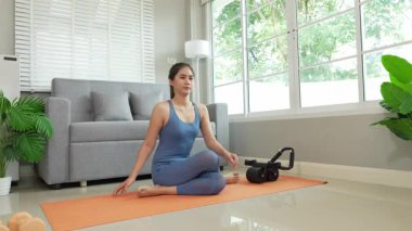 Sağlık, fitness konsepti. Aktif Asyalı bayan sporcu evde egzersiz yapıyor, mindere oturuyor. Spor ve spor rutini.