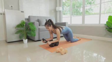 Sağlık, fitness konsepti. Aktif Asyalı bayan sporcu evde egzersiz yapıyor, mindere oturuyor. Spor ve spor rutini.