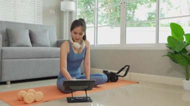 Sağlık, fitness konsepti. Aktif Asyalı bayan sporcu evde egzersiz yapıyor, mindere oturuyor. Spor ve spor rutini.