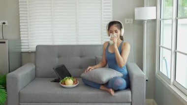 Asyalı kadın evindeki video konferansında sağlıklı beslenme ve egzersiz yapmayı teşvik ediyor. Sağlıklı yaşam tarzı kavramı.