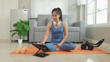 Sağlık, fitness konsepti. Aktif Asyalı bayan sporcu evde egzersiz yapıyor, mindere oturuyor. Spor ve spor rutini.