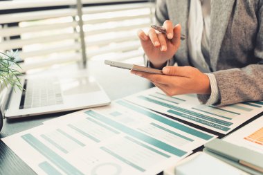 Çizelgeleri ve finansal verileri hesap makinesi ve dizüstü bilgisayarla inceleyen ve inceleyen profesyonel bir kadın. Masasında kağıt belgelerle çalışan genç bir kadının yakın çekimi..