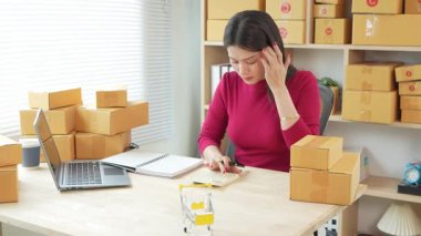 Evde kutu paketlerken dijital tablet üzerinde çevrimiçi satışlara ve müşteri hizmetlerine odaklanan dizüstü bilgisayarlı KOBİ girişimcisi. Pazarlama için sosyal medyayı kullanmak. İnternetten alışveriş.